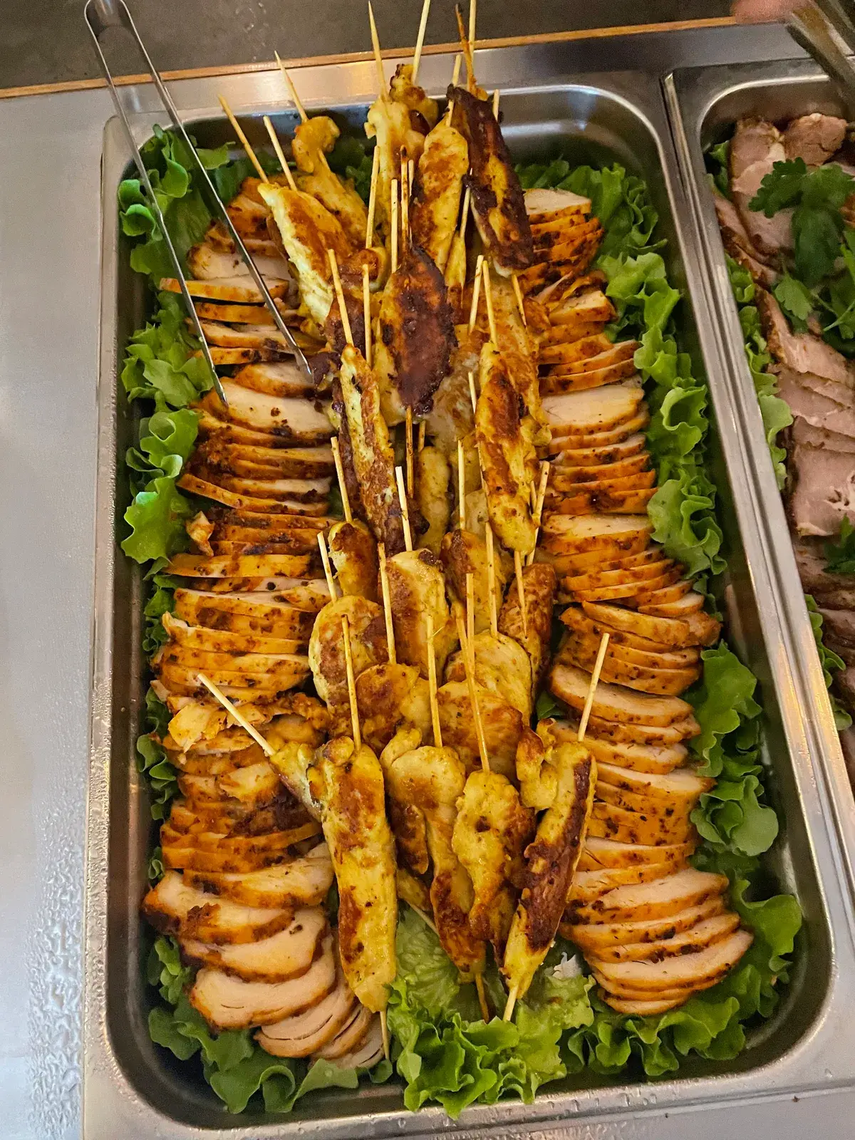 Grillade kycklingspett och skivad kycklingfilé på salladsbädd